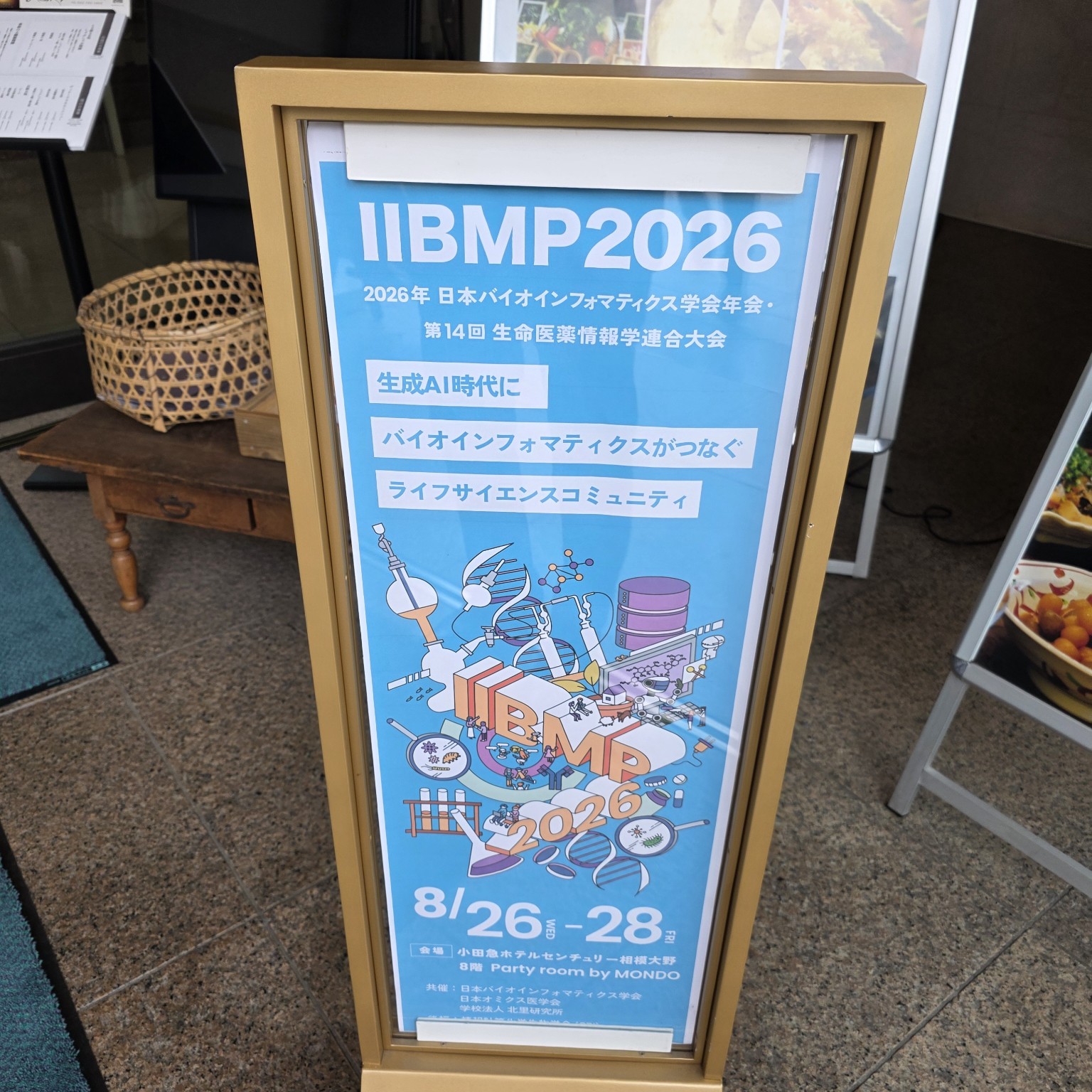 IIBMP2026会場入口に掲示された大会案内。「生成AI時代にバイオインフォマティクスがつなぐライフサイエンスコミュニティ」と書かれている。