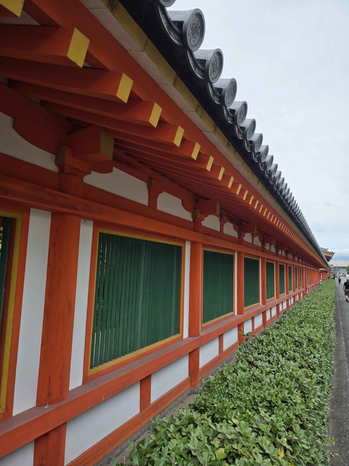 朱色の柱と梁、緑色の建具、黄色の装飾が並ぶ古い寺社建築